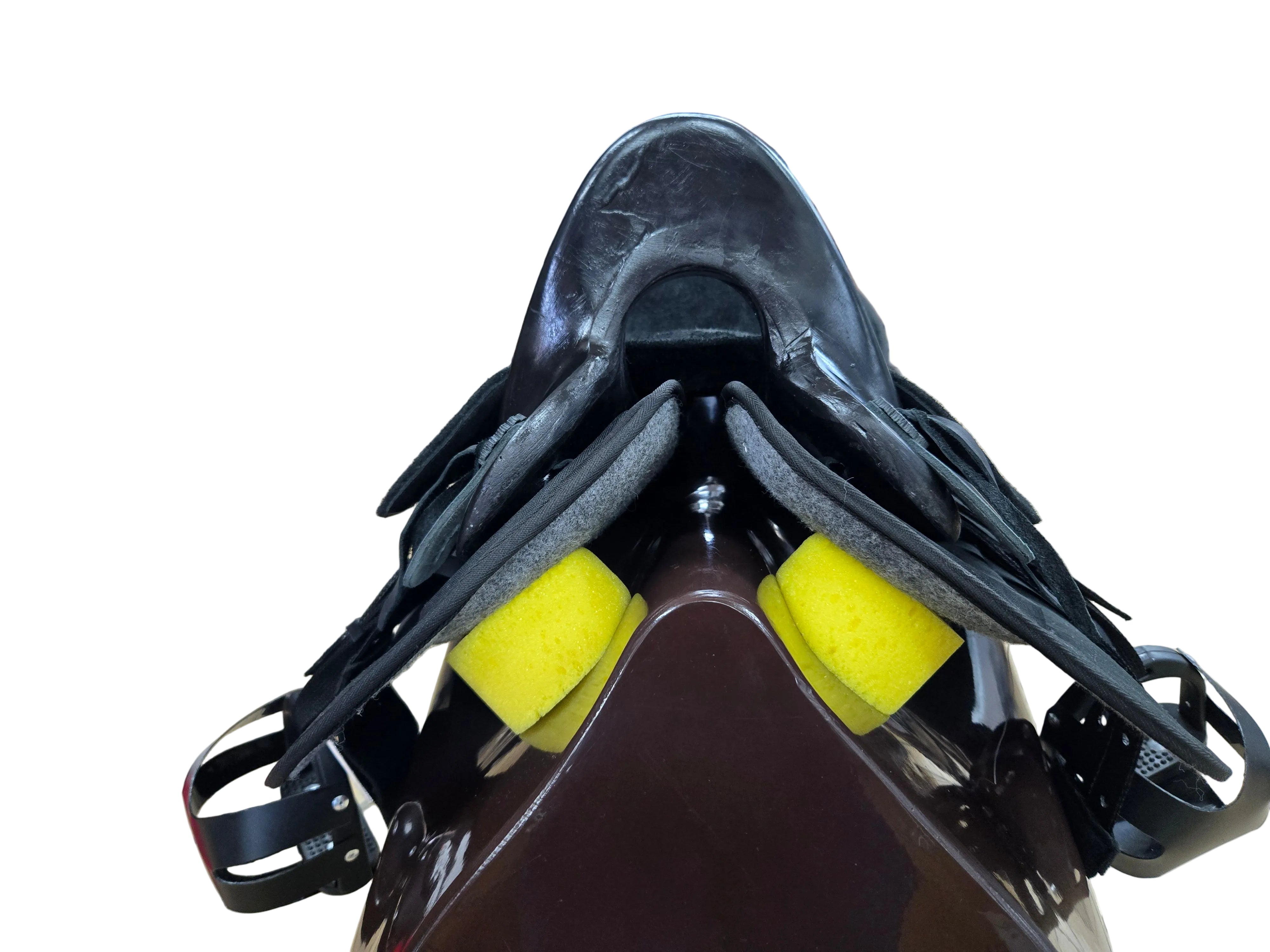 A close-up of a black leather saddle with black leather straps and bright yellow foam inserts, photographed inside a retail store with shelves and other tack visible in the background.